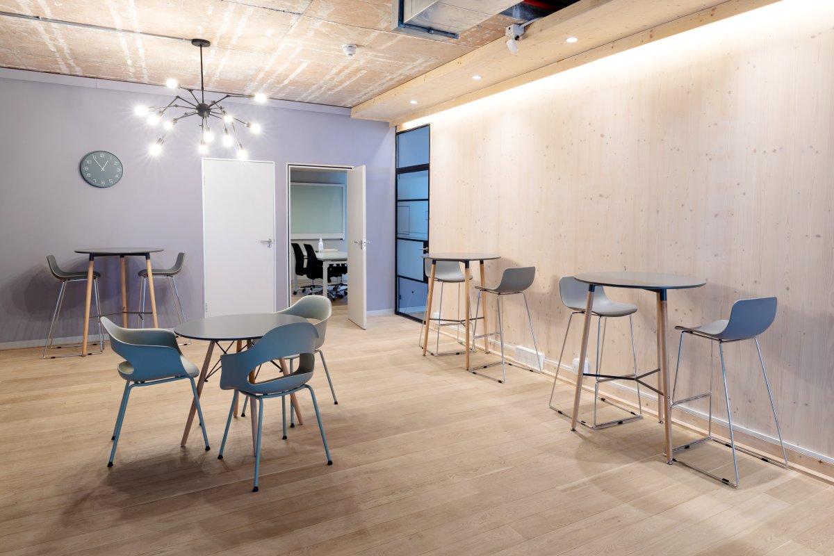 Empty chairs arranged around tables on hardwood floor in illuminated office. business and office workplace.