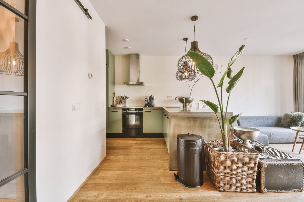 Interior of spacious light dining room and elegant chandelier located near kitchen with modern furniture and appliances